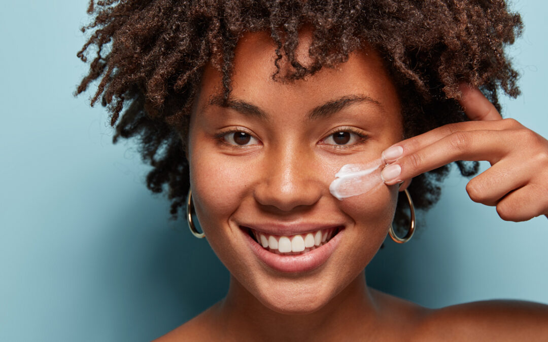 Model applying moisturizer to her face - True Clean Beauty